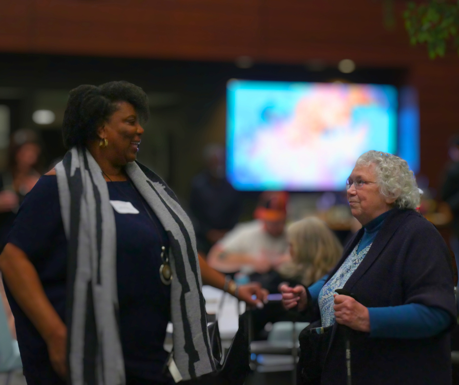 Two individuals speaking with one another at event.
