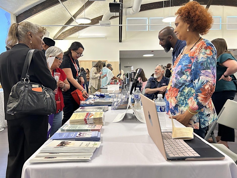 Several people gathered around table covered in various flyers