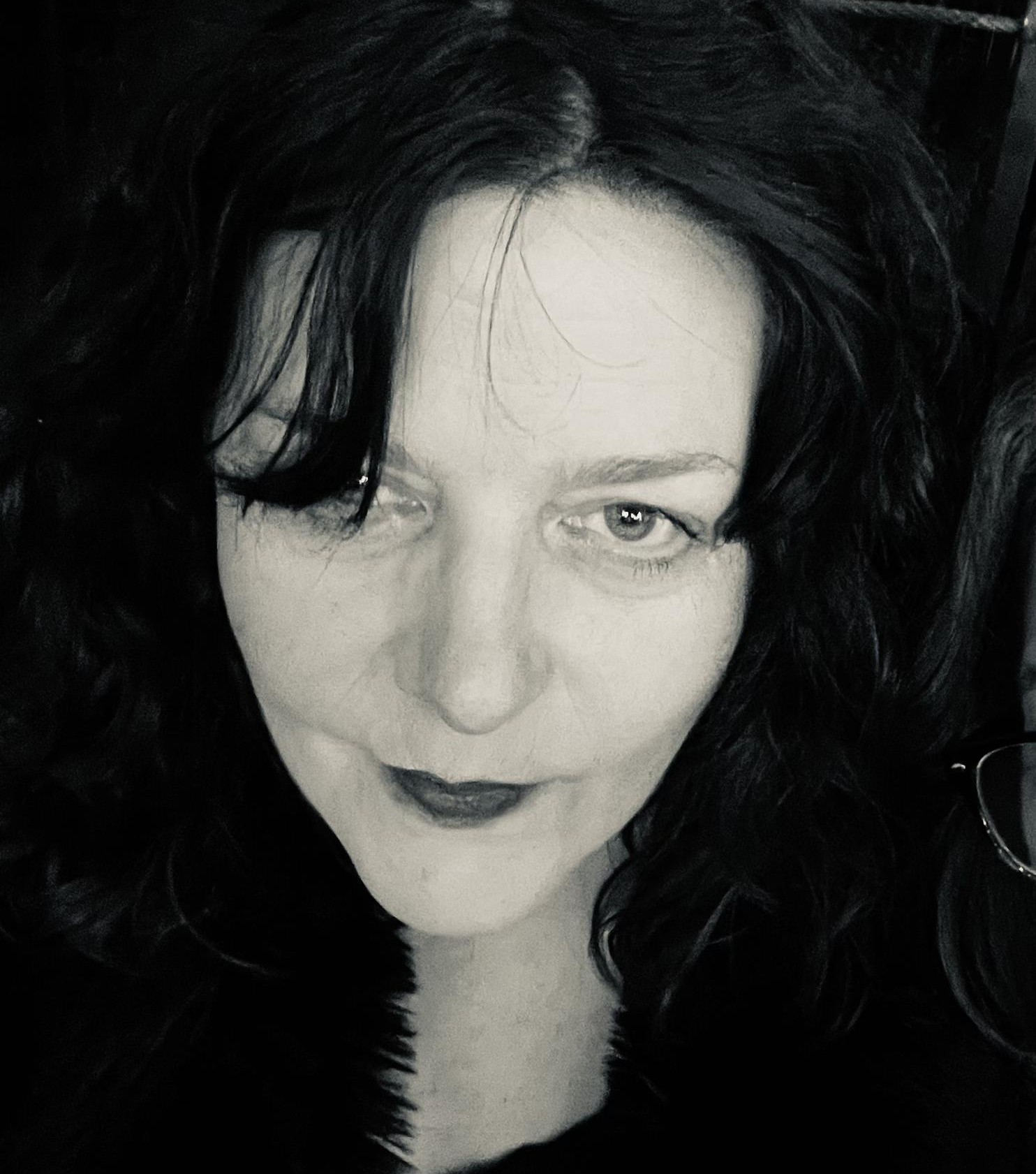 Closeup B&W photo of Caroline, a white woman with dark bangs covering one eye